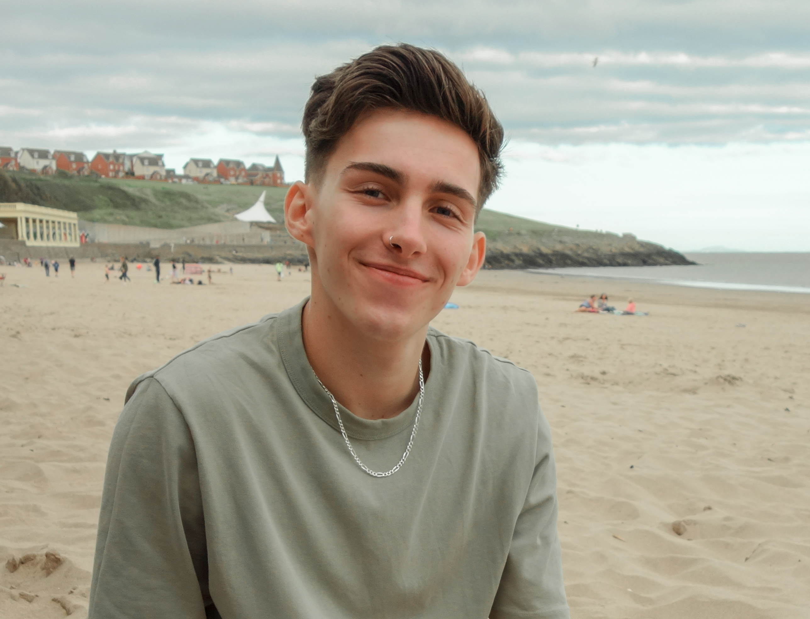 Photograph of Kamil Rog, smiling and sitting on a beach